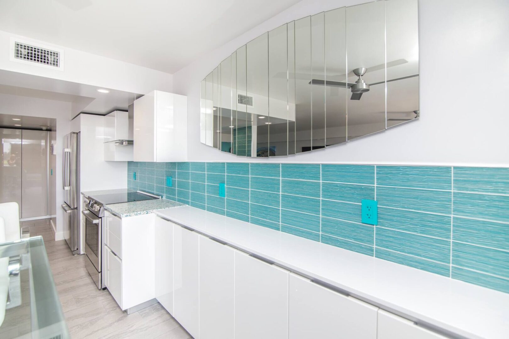 A kitchen with blue tile and white cabinets.