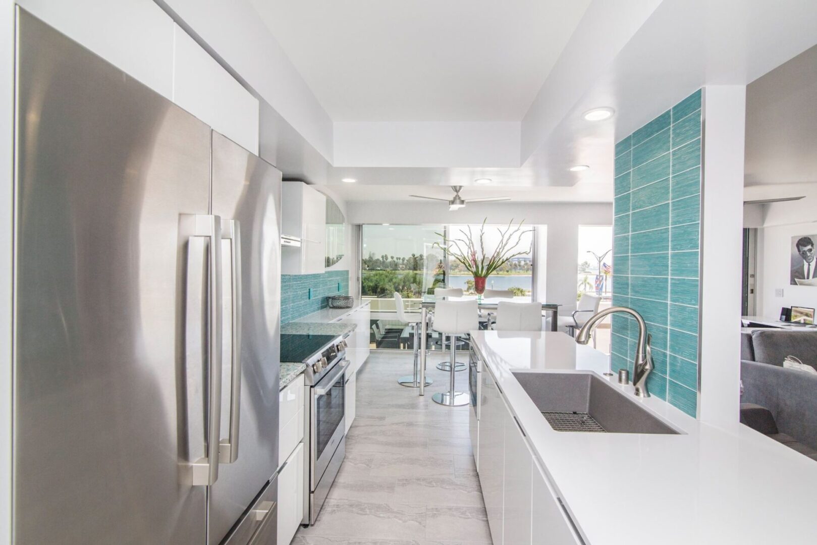 A kitchen with white cabinets and blue tile walls.