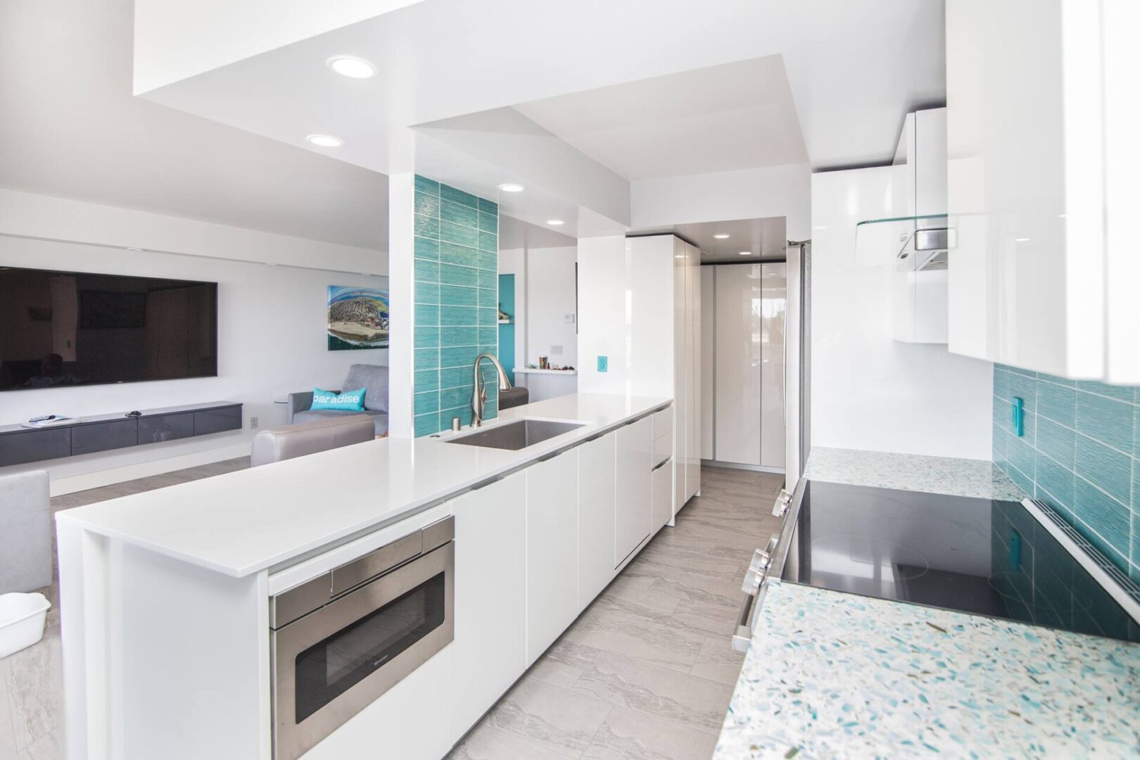 A kitchen with white cabinets and blue glass tile.