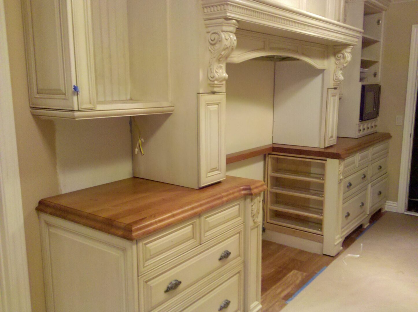 A kitchen with white cabinets and wood counters.