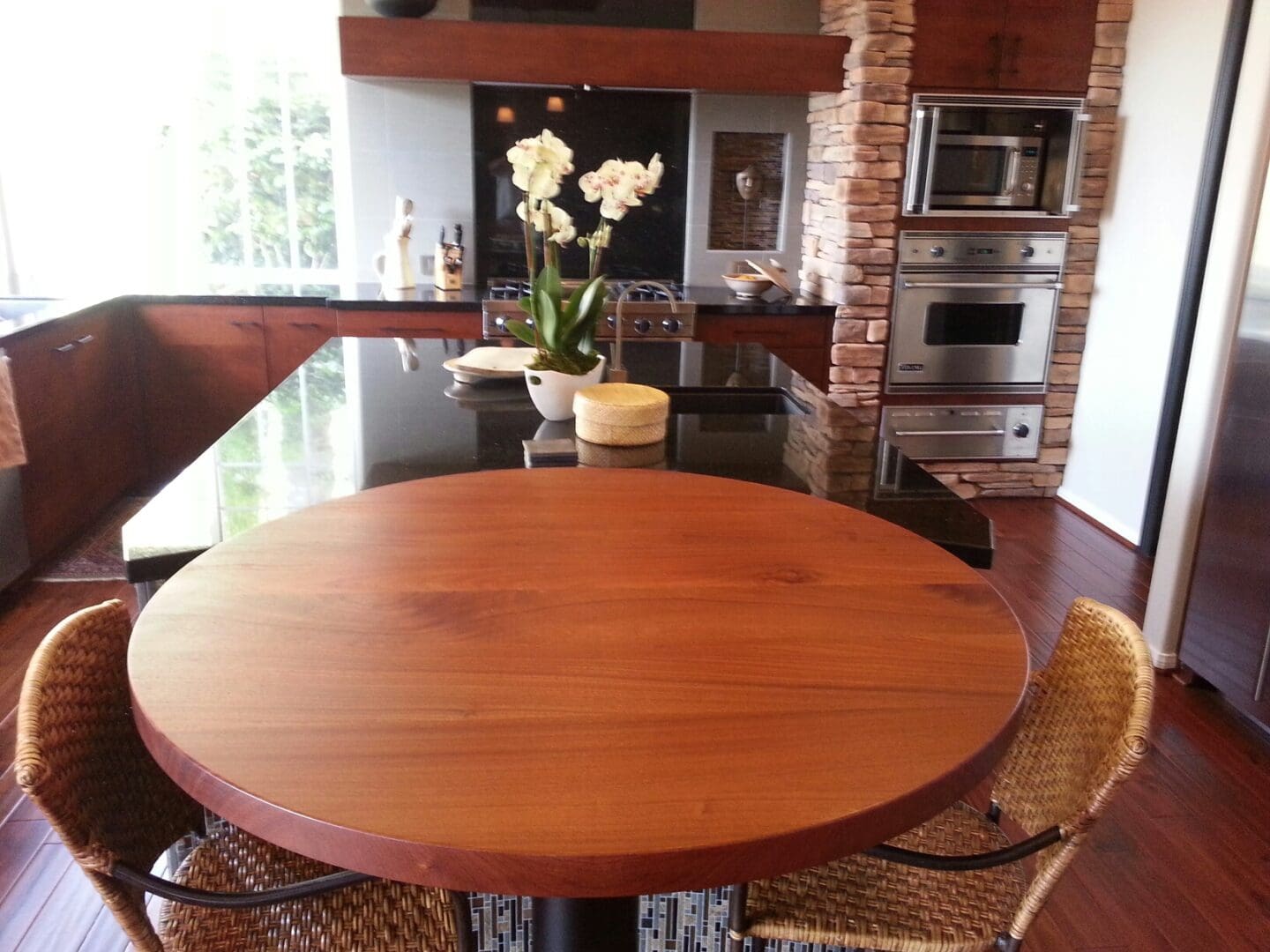 A table with chairs and a vase of flowers on top.