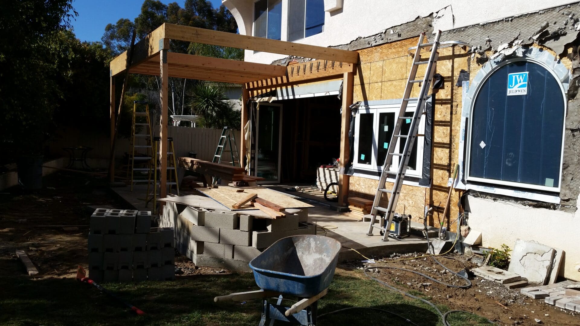 A house being built with a deck and patio in the background.