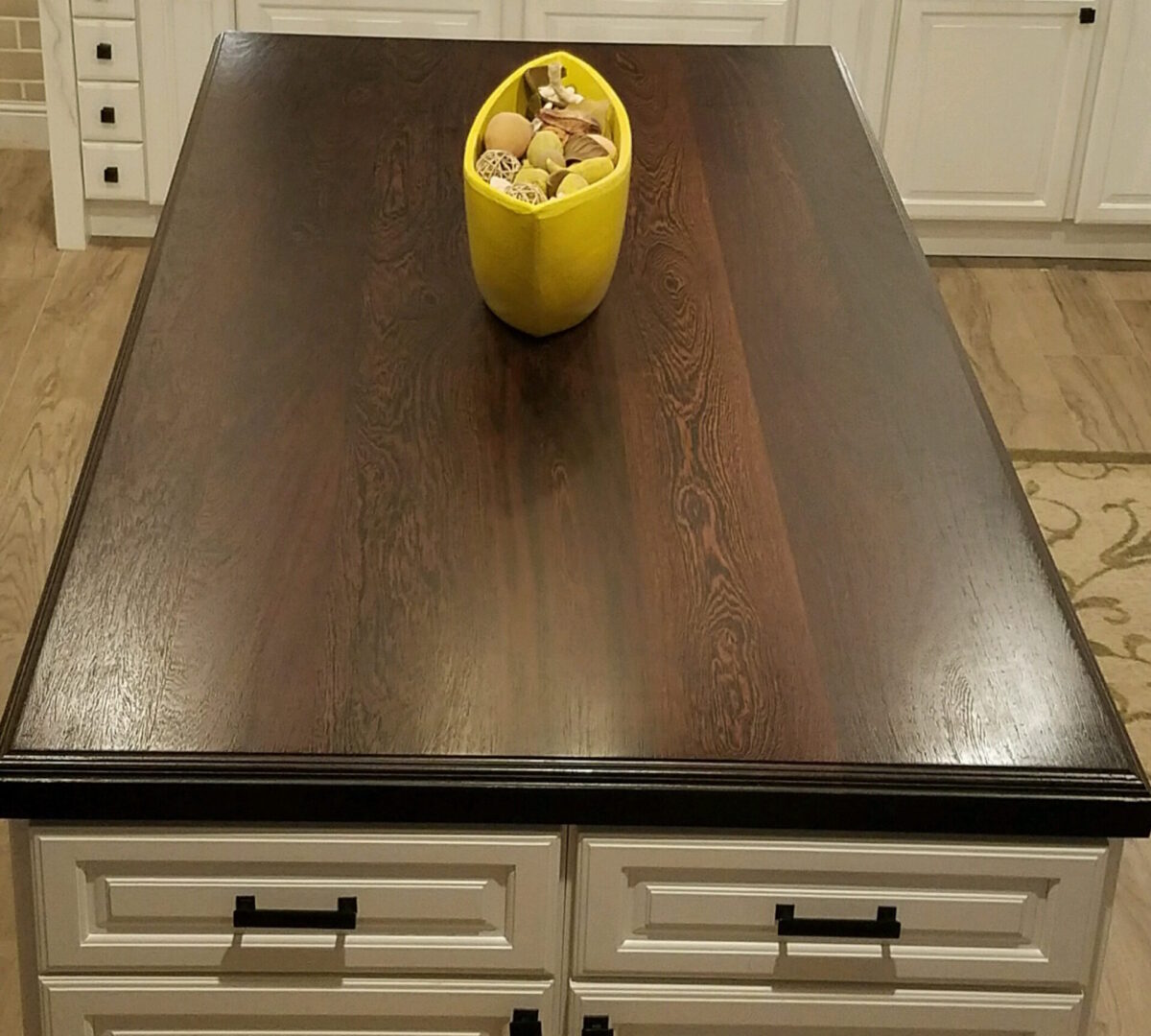 A wooden table with a yellow vase on top of it.