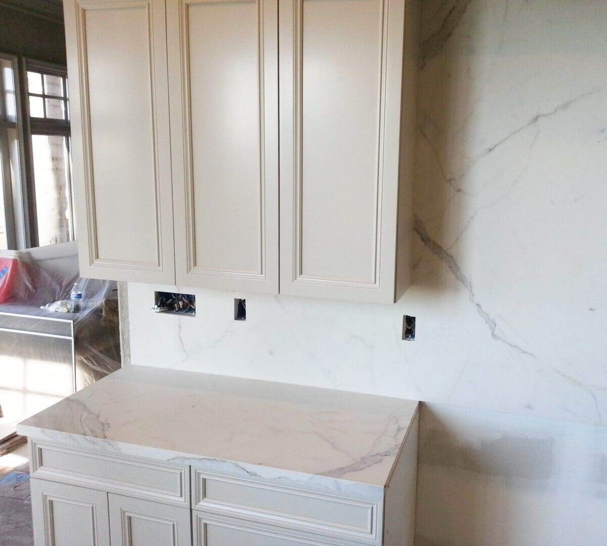 A kitchen with white cabinets and walls in the process of being remodeled.