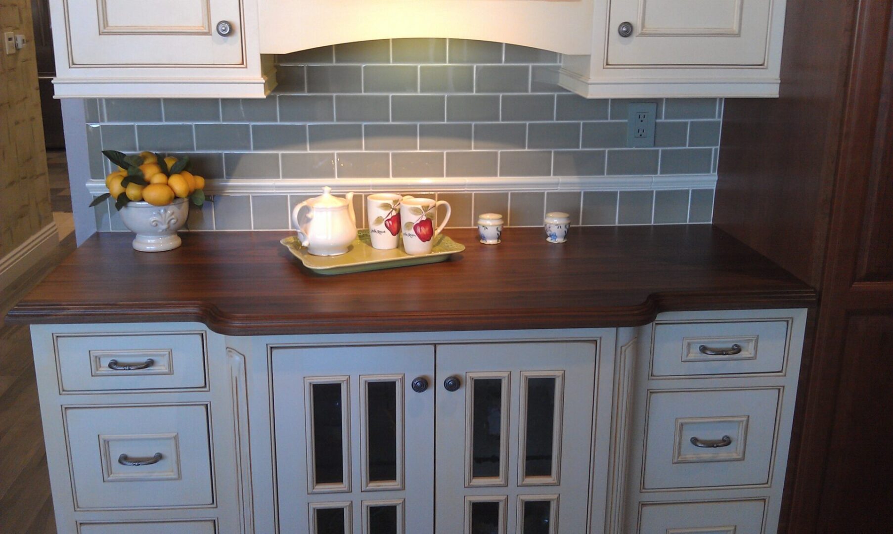 A kitchen with white cabinets and wooden counter tops.