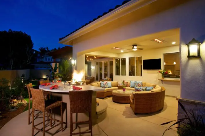 A patio with furniture and a television on the wall.