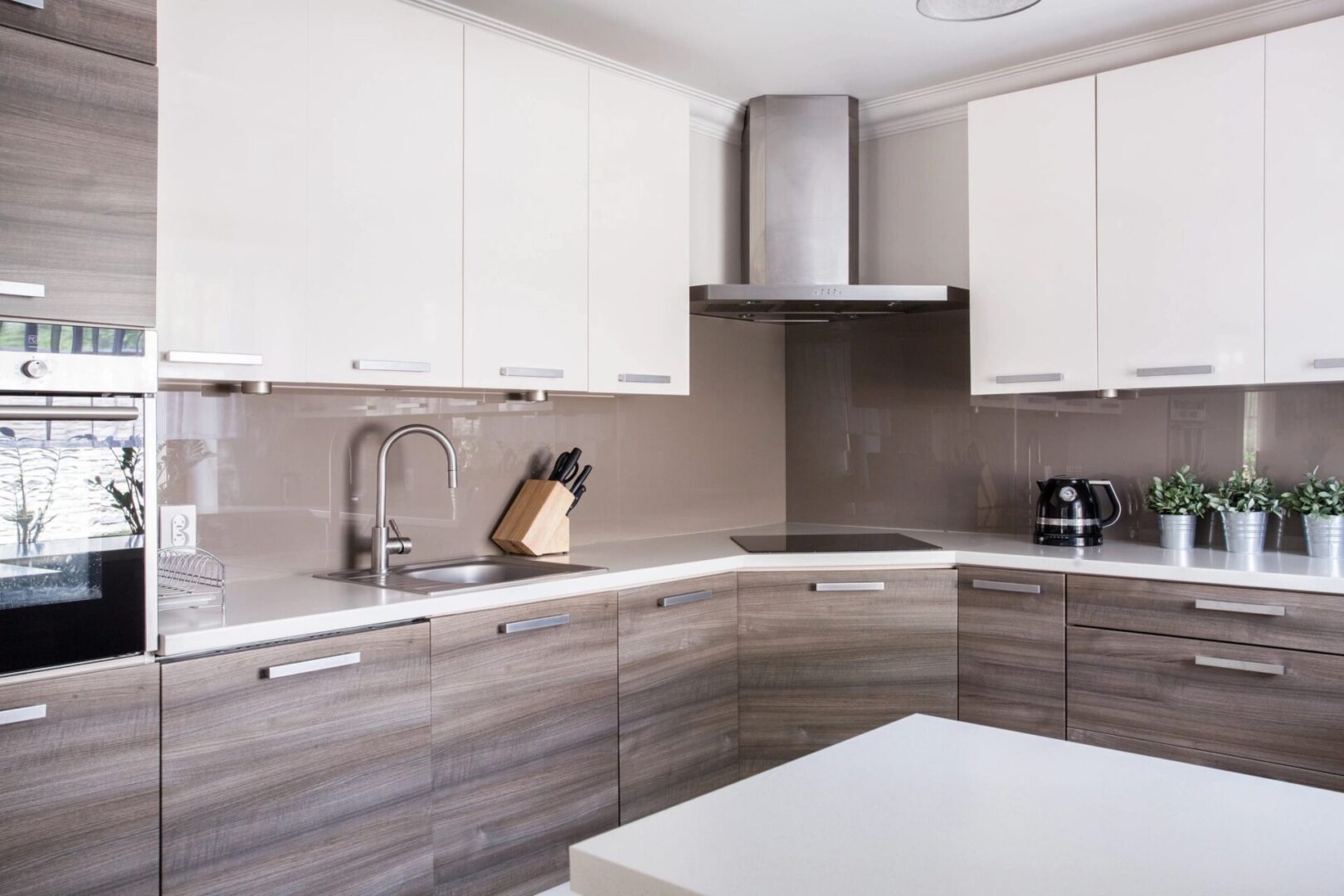 A kitchen with white and brown cabinets, a sink and a counter.