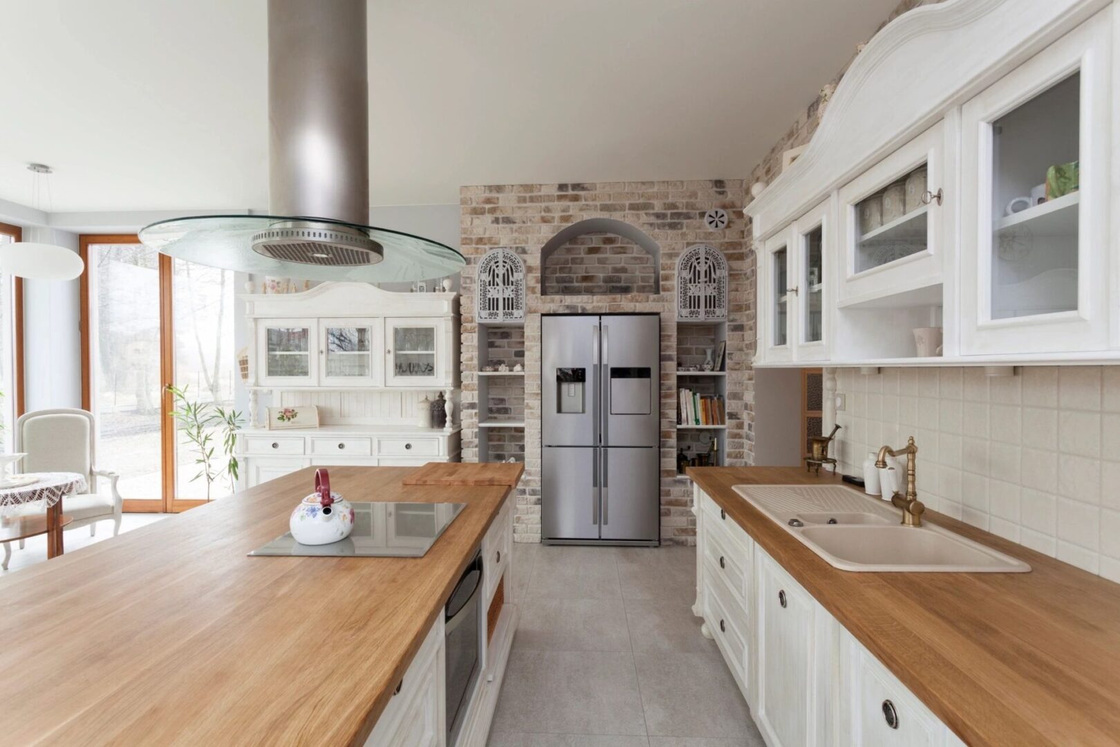 A kitchen with white cabinets and wood countertops.